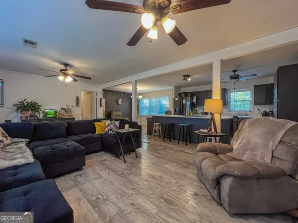 a living room with furniture kitchen view and a chandelier