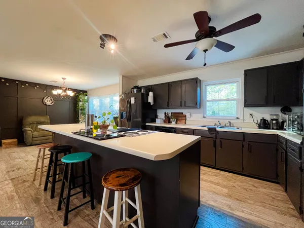 a kitchen with stainless steel appliances granite countertop a sink a stove a refrigerator a microwave oven with white cabinets and wooden floor