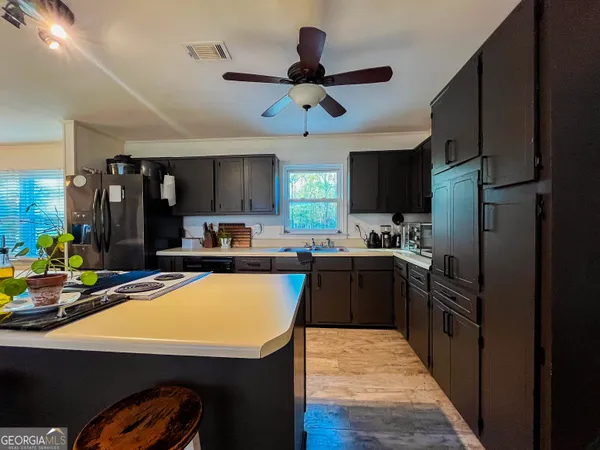 a kitchen with stainless steel appliances kitchen island granite countertop a refrigerator a sink dishwasher a stove and a refrigerator