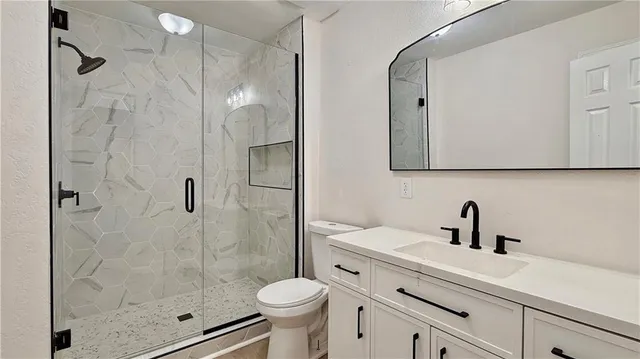 a bathroom with a shower sink vanity mirror and toilet