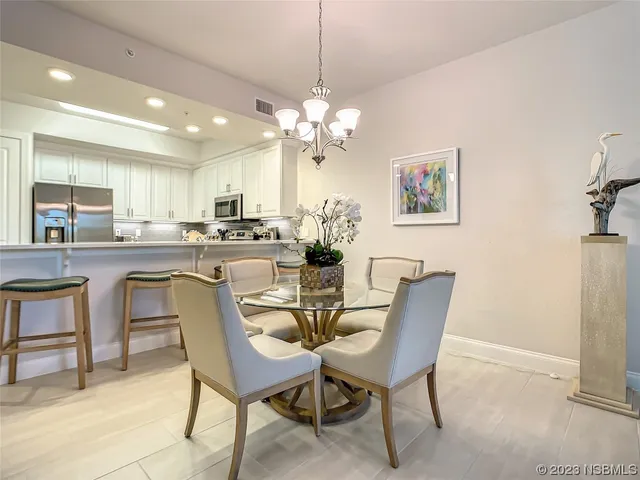a dining room filled chandelier and kitchen view