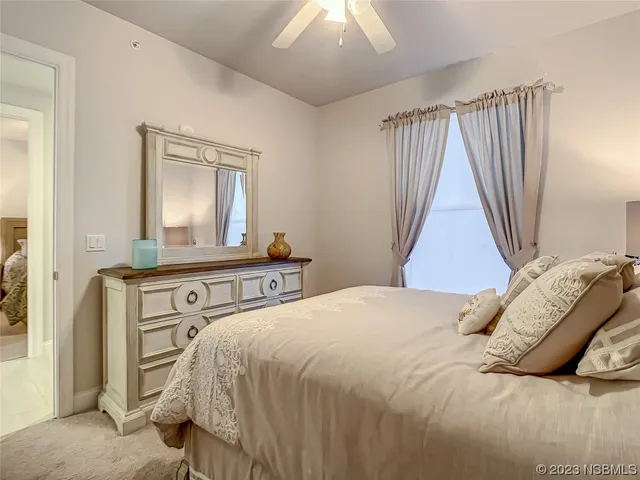 a large bed sitting in a bedroom next to a window and a chandelier