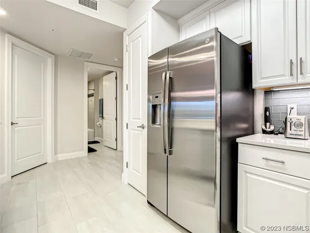 a kitchen with stainless steel appliances a table chairs refrigerator and microwave