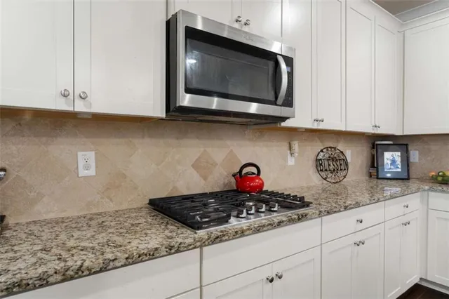 a kitchen with stainless steel appliances granite countertop white cabinets and a stove