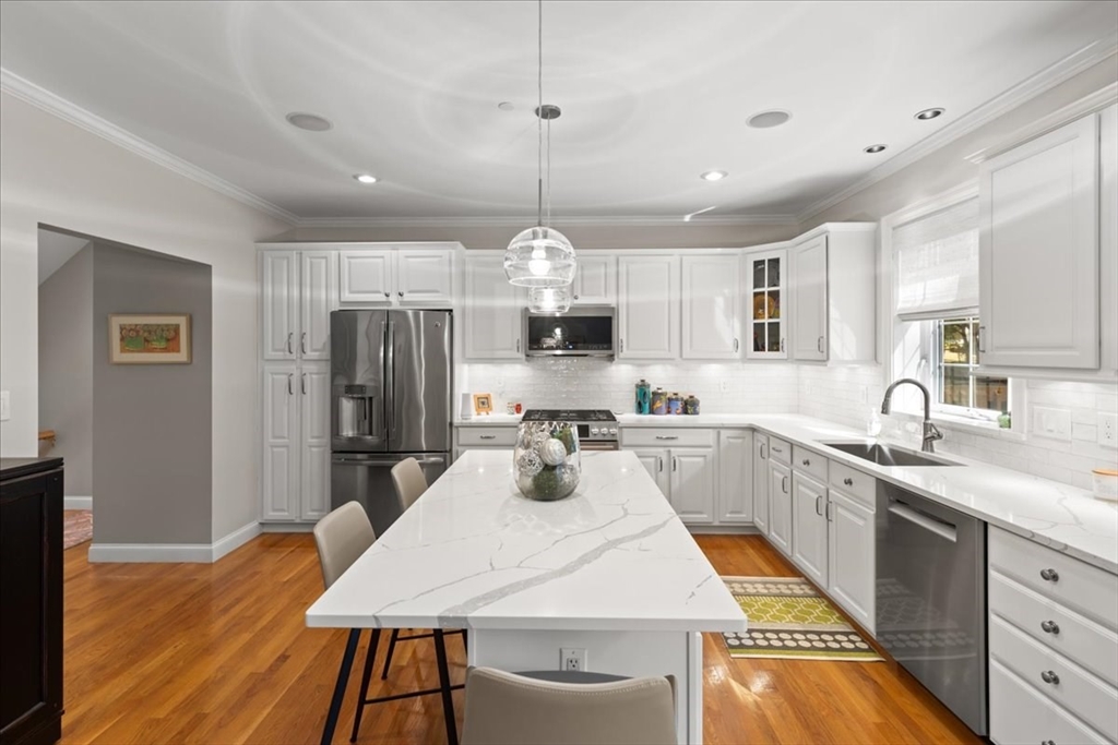 923 Lagrange Street, Unit 923 Boston, MA 02132 - Photo 13 of 32 a kitchen with stainless steel appliances a dining table chairs sink and refrigerator