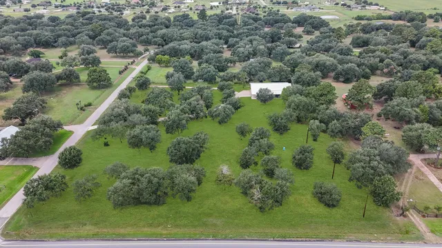 an aerial view of a residential houses with outdoor space and trees