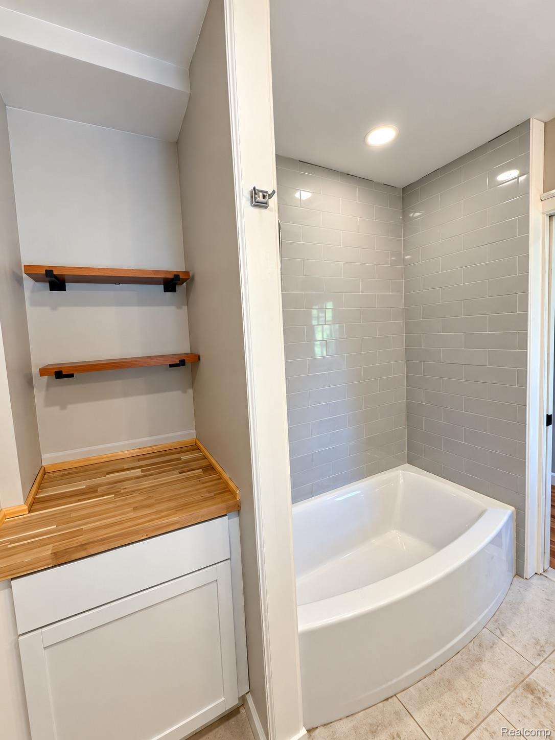 3208 Lothrop Detroit, MI 48206 - Photo 24 of 41 Built-in storage cabinet with wood-finish countertop, wood-finish floating shelves, and white soaking tub with subway tile surround