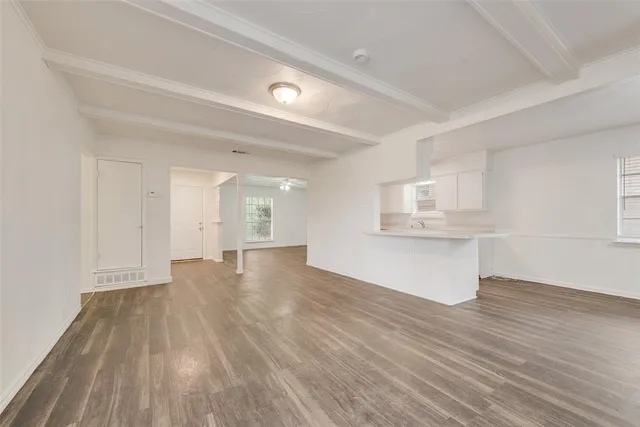 a view of kitchen and empty room with wooden floor