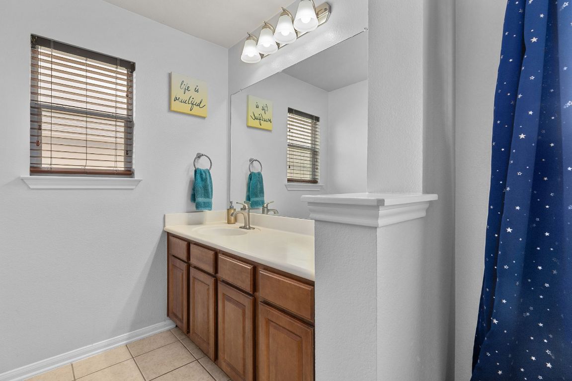 701 Old Ravine Court Round Rock, TX 78665 - Photo 24 of 40 Full bathroom featuring vanity, light tile patterned floors, and curtained shower