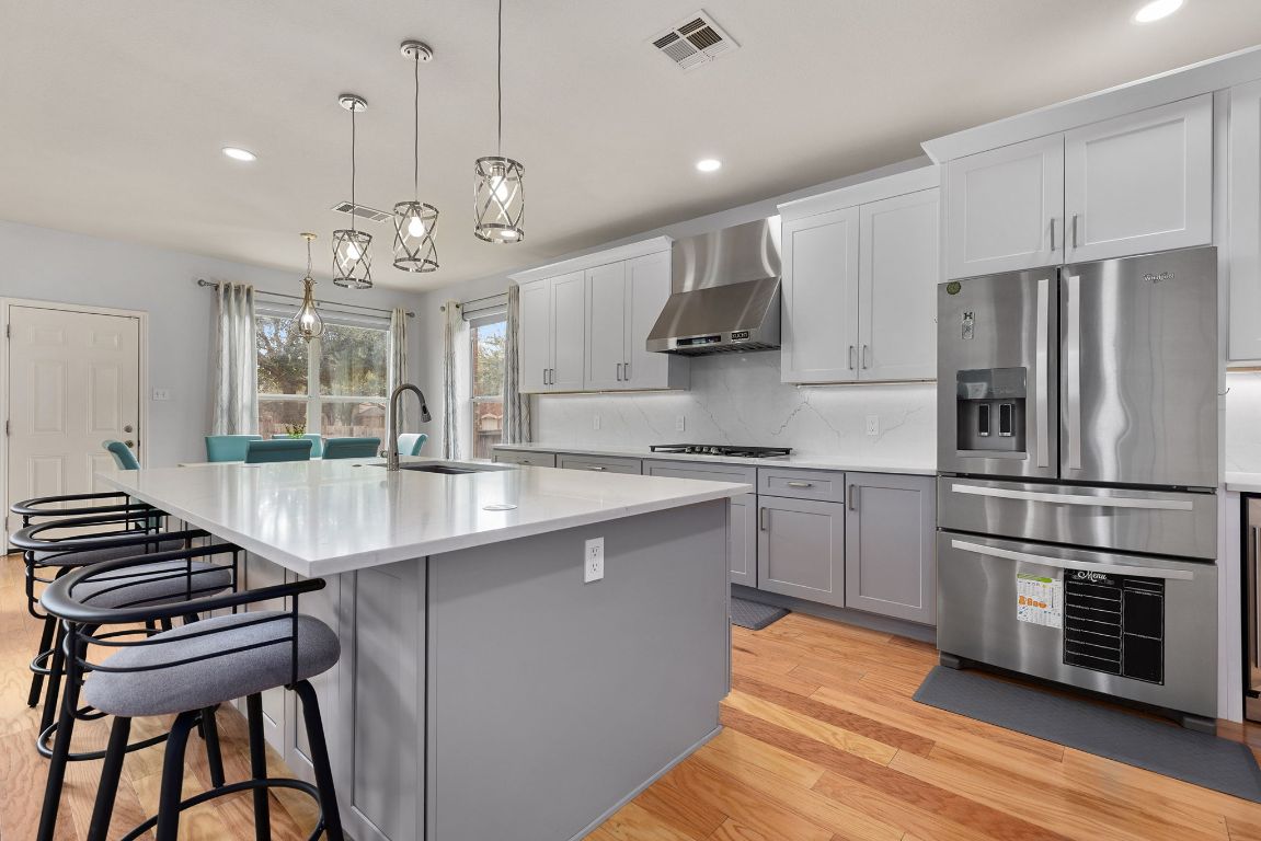 701 Old Ravine Court Round Rock, TX 78665 - Photo 3 of 40 Kitchen with stainless steel fridge, light wood-type flooring, gray cabinets, hanging light fixtures, and white cabinetry