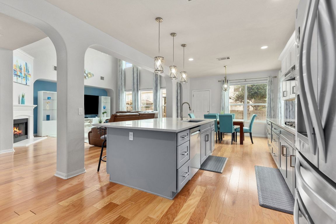 701 Old Ravine Court Round Rock, TX 78665 - Photo 39 of 40 Kitchen with hanging light fixtures, stainless steel appliances, a breakfast bar, light wood-style floors, and open floor plan