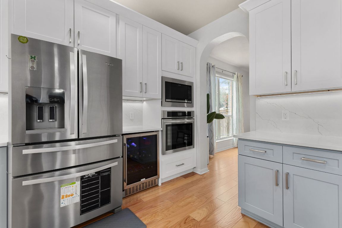 701 Old Ravine Court Round Rock, TX 78665 - Photo 7 of 40 Kitchen featuring appliances with stainless steel finishes, beverage cooler, and white cabinets