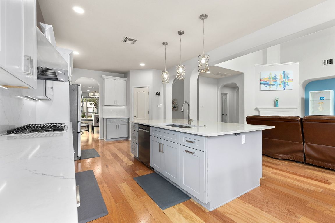 701 Old Ravine Court Round Rock, TX 78665 - Photo 40 of 40 Kitchen with arched walkways, light wood finished floors, open floor plan, pendant lighting, and light stone counters