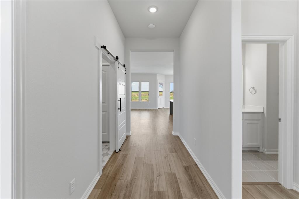 104 Snowy Owl Trail Rhome, TX 76078 - Photo 5 of 27 Hallway featuring wood-finish flooring, recessed lighting, and a modern barn door