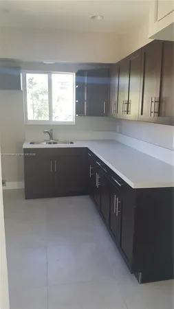 a large kitchen with granite countertop a sink and cabinets