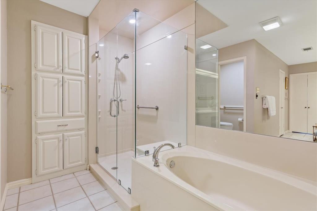 4108 Old Mill Road Waco, TX 76710 - Photo 24 of 39 Spa-inspired primary bathroom featuring an updated frameless glass-enclosed shower with chrome fixtures, dual vanity countertop and integrated sink, large soaking tub, and abundant light from recessed ceiling fixtures