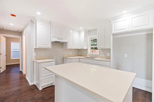 a large kitchen with cabinets wooden floor and stainless steel appliances