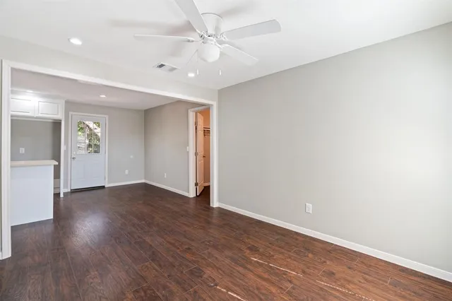 an empty room with wooden floor and ceiling fan