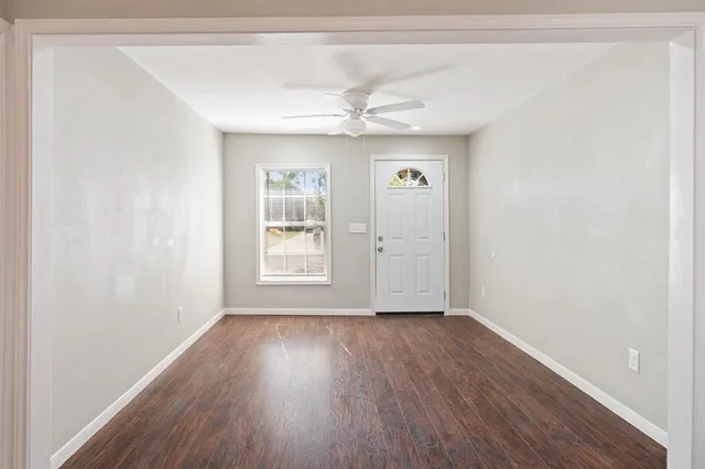 an empty room with wooden floor chandelier fan and windows