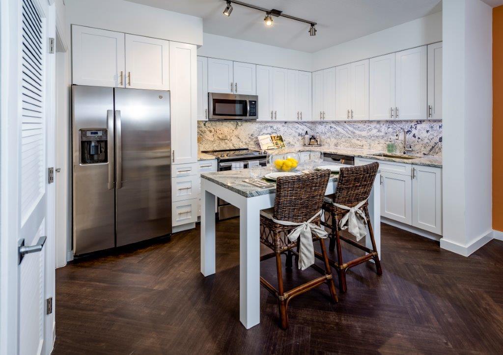 a kitchen with stainless steel appliances a table chairs microwave and refrigerator