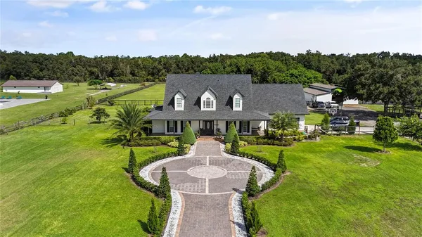 a view of a big house with a big yard and large trees