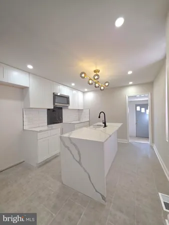 a large white kitchen with kitchen island a sink stainless steel appliances and a fireplace