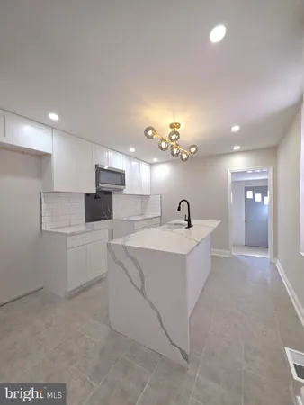 a large white kitchen with kitchen island a sink stainless steel appliances and a fireplace