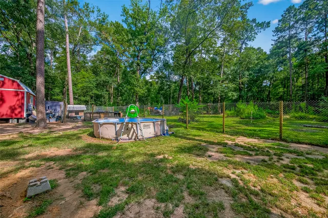 a view of backyard with wooden fence and a large tree