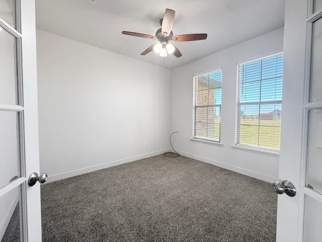 an empty room with windows and fan