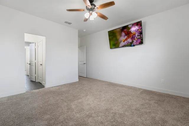 an empty room with windows and fan