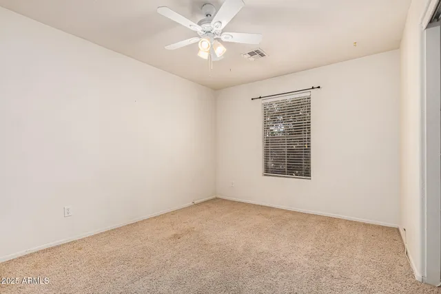 an empty room with a ceiling fan and a window