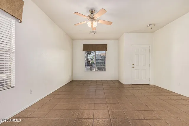 an empty room with chandelier fan and windows