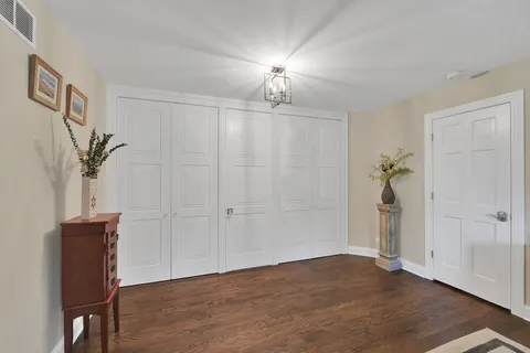 a view of an empty room with wooden floor and closet