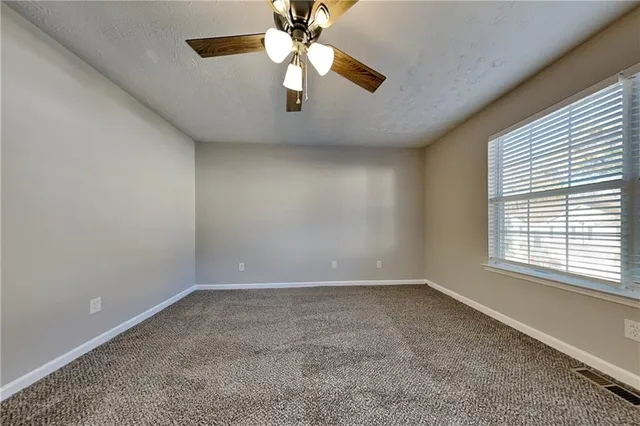 an empty room with a window and a ceiling fan