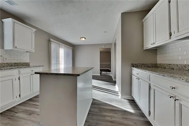 a kitchen with granite countertop white cabinets and white appliances
