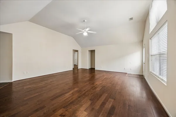 an empty room with wooden floor and windows