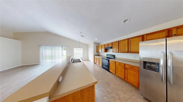 a large kitchen with stainless steel appliances wooden floor a large window and a sink