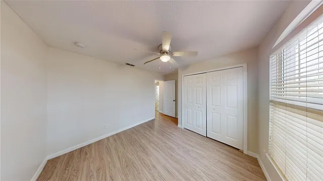 an empty room with wooden floor and windows