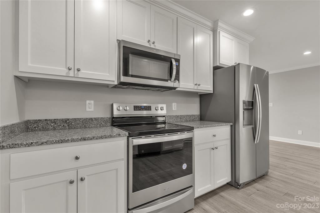 6724 State Rd S-29-555 Kershaw, SC 29067 - Photo 7 of 31 a kitchen with stainless steel appliances granite countertop white cabinets and a stove a refrigerator with wooden floor