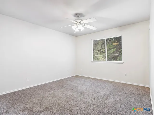 an empty room with a chandelier fan and windows
