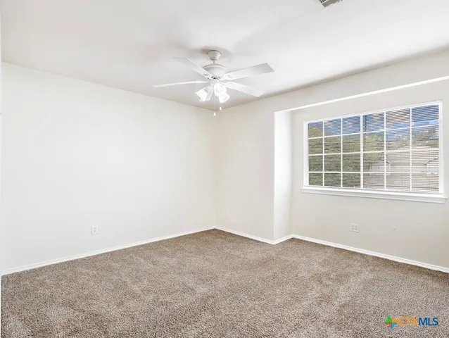 an empty room with a window and a fan