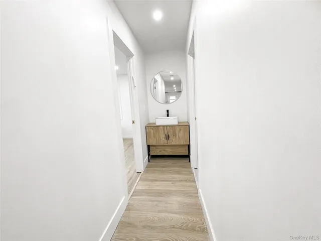 a view of a hallway with wooden floor and a bathroom