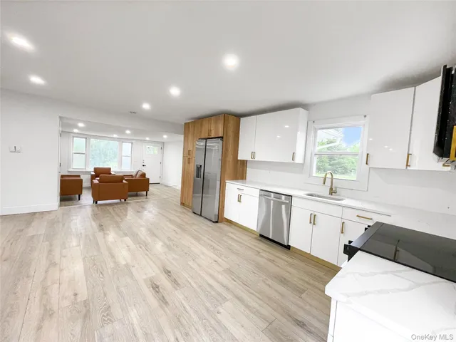 a large white kitchen with a refrigerator a stove a sink dishwasher and a oven with wooden floor