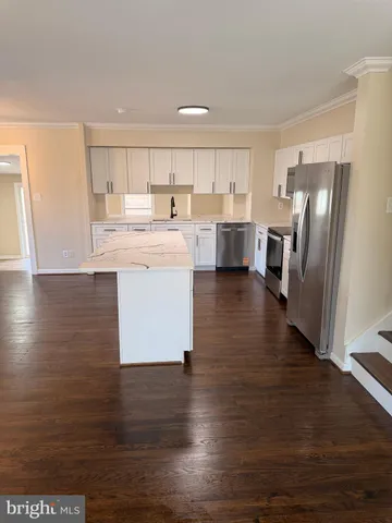 a kitchen with stainless steel appliances granite countertop a refrigerator a sink dishwasher a stove and a refrigerator with wooden floor