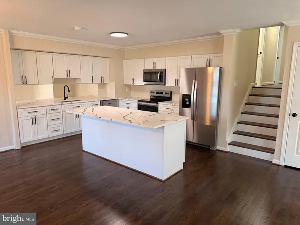 a large kitchen with stainless steel appliances granite countertop a stove top oven a refrigerator a sink and dishwasher with wooden floor