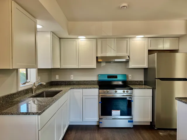 a kitchen with granite countertop a stove sink and refrigerator