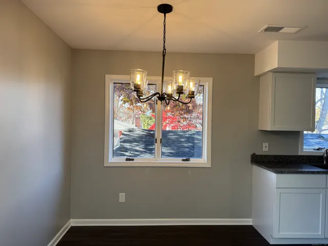 a view of empty room with window and chandelier fan