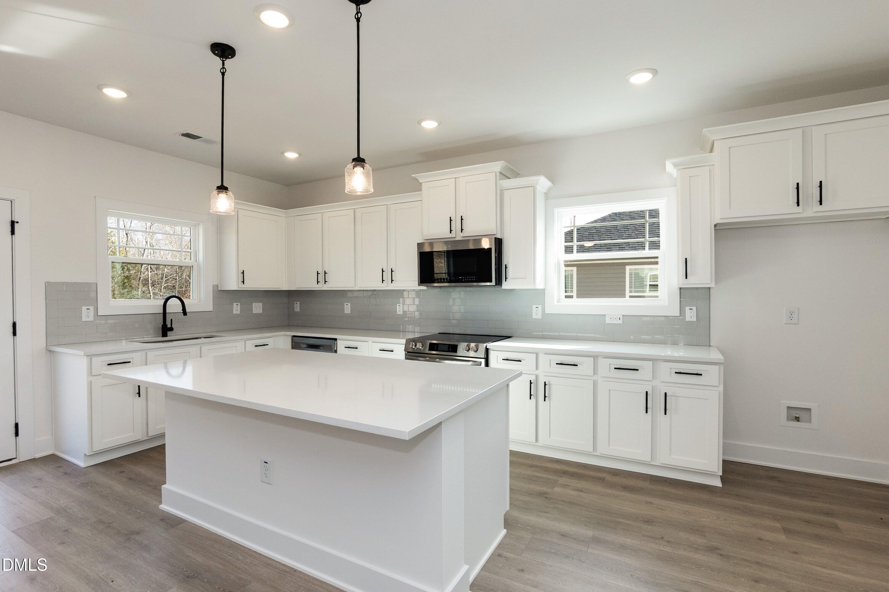 42 Braddock Court Garner, NC 27529 - Photo 11 of 56 a kitchen with a stove a sink a microwave and wooden floors