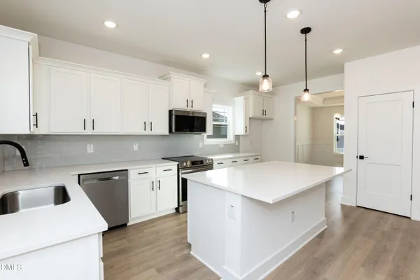 a large kitchen with granite countertop a stove top oven a sink a dining table and chairs