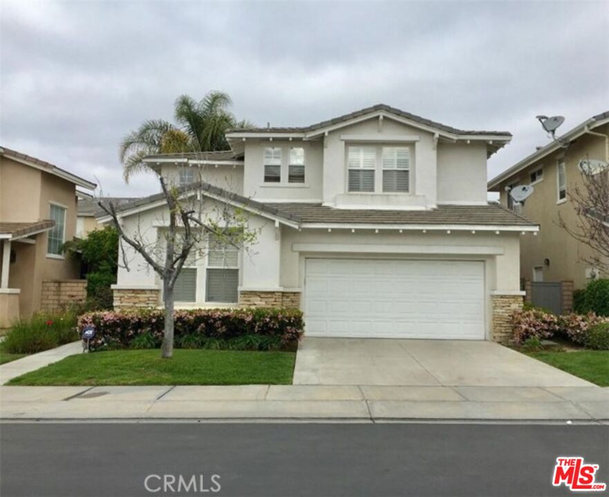 a front view of a house with garage and plants